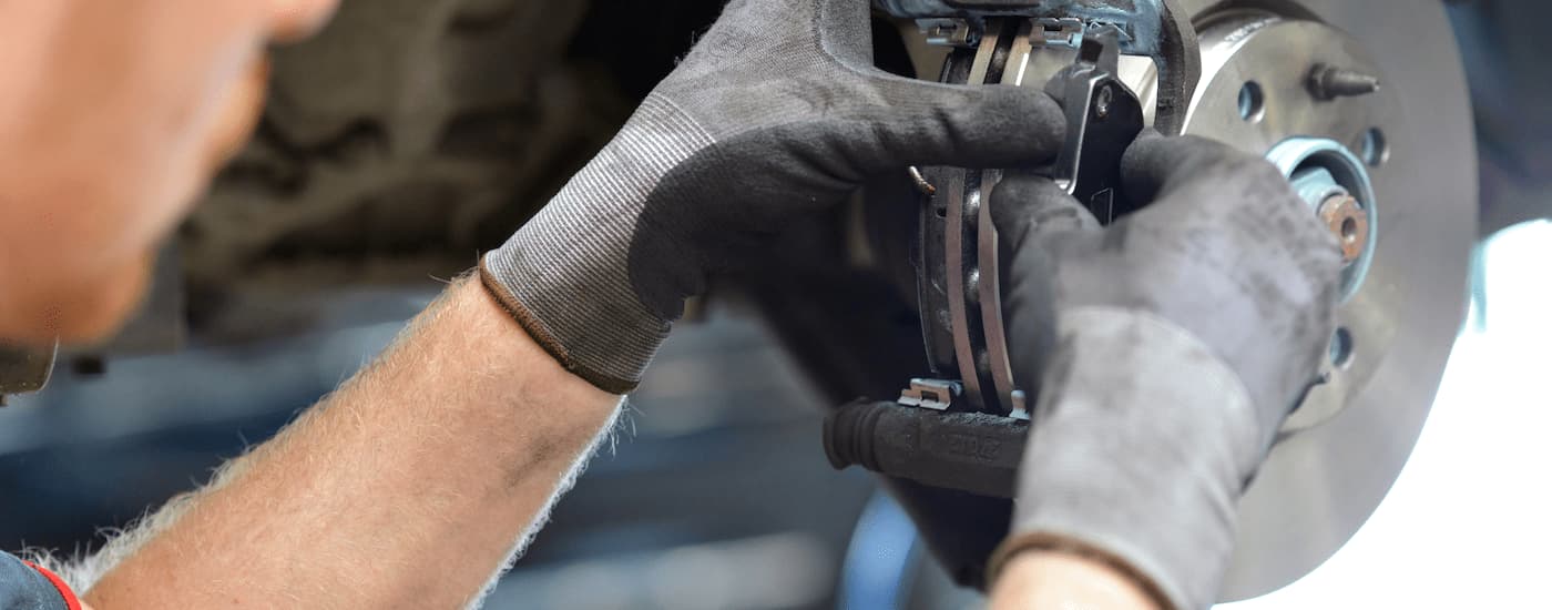 A close up of a mechanic inspecting a set of brakes is shown.