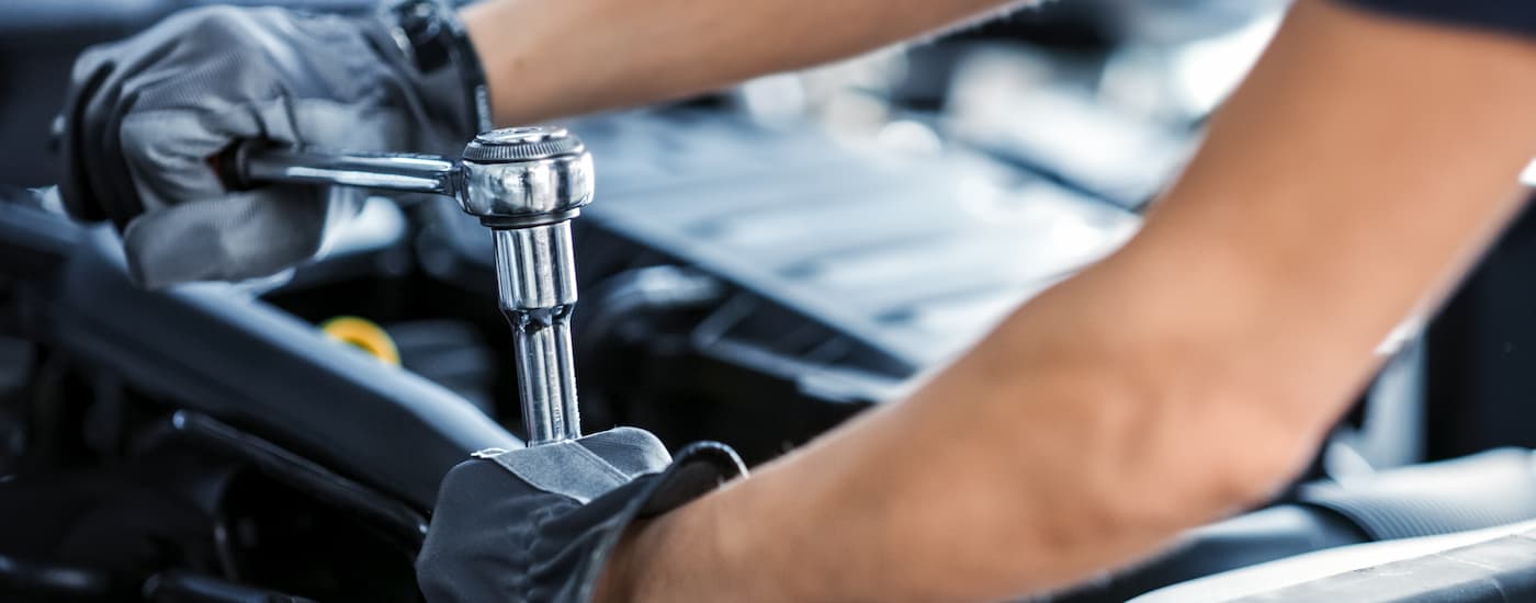A close up of a mechanic working on a car engine is shown.