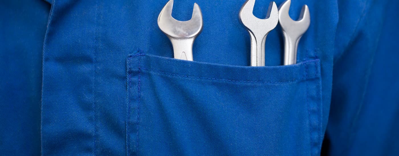 A close up of a set of wrenches are shown in the pocket of a certified Jeep mechanic.