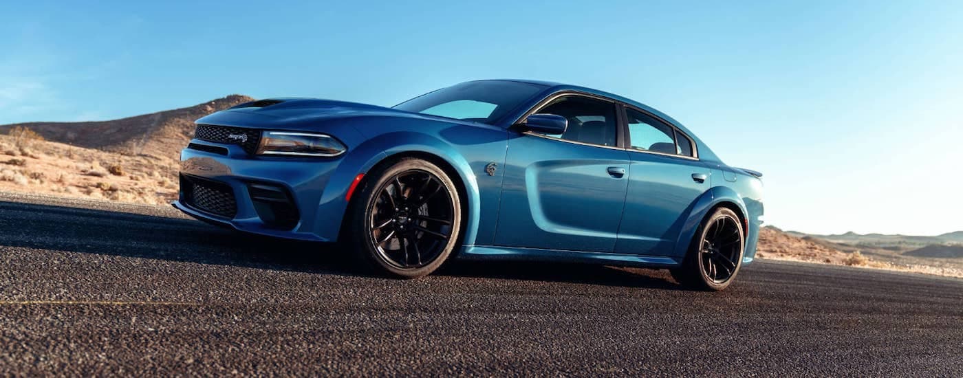 A blue 2021 Dodge Charger is shown from the side driving on pavement.