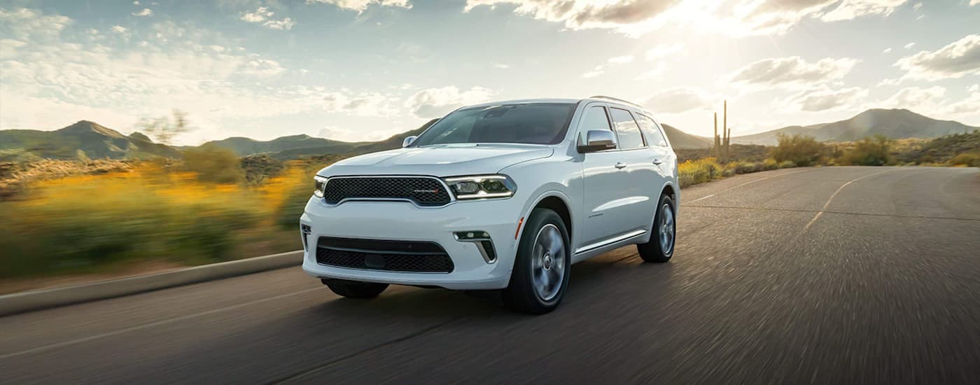 A white 2022 Dodge Durango is shown driving on a sunny day.