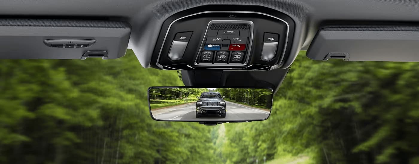A grey 2023 Jeep Grand Cherokee L is shown in the rear view mirror of an SUV.
