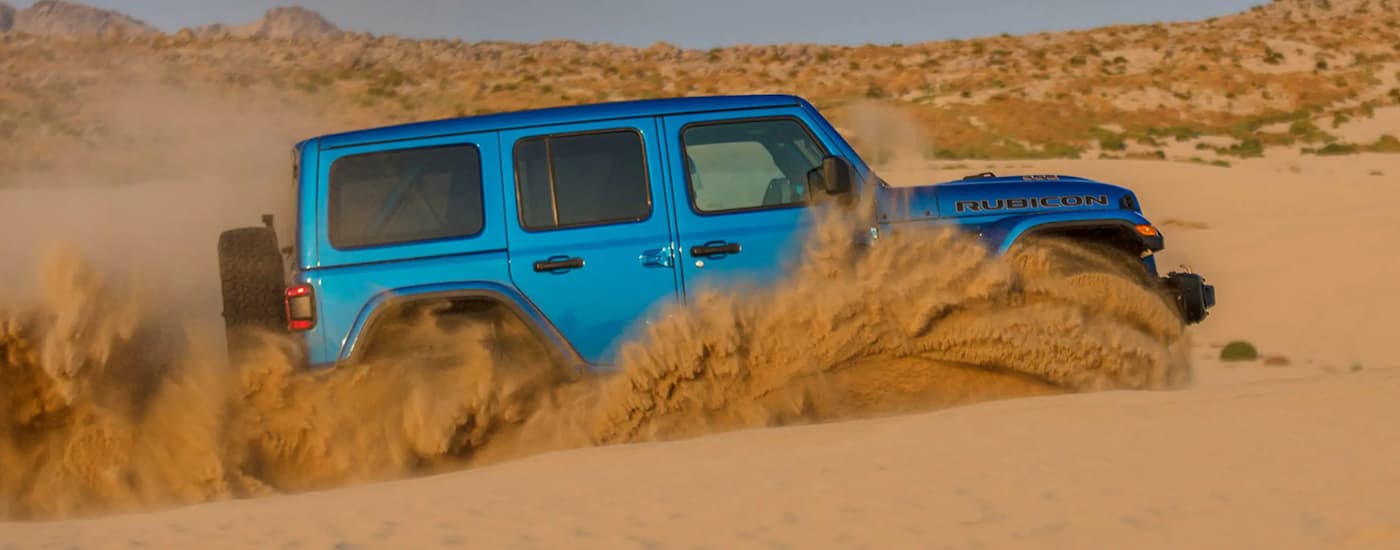 A blue 2021 Jeep Wrangler Rubicon 392 is shown off-roading in the desert after leaving a NJ Jeep Wrangler dealer.