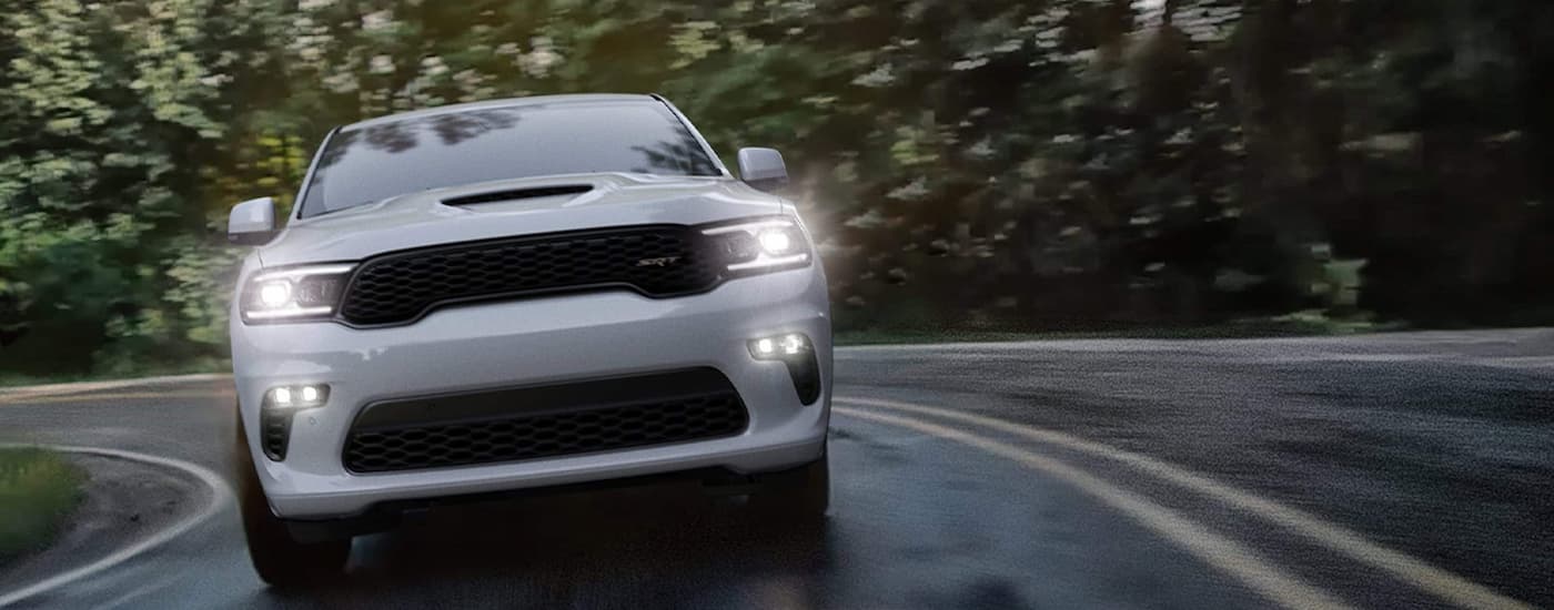 A white 2022 Dodge Durango SRT is shown from the front driving on a winding road after leaving an SUV dealer near you.