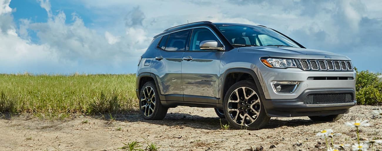 A silver 2020 Jeep Compass is shown angled right while parked on a sandy beach.