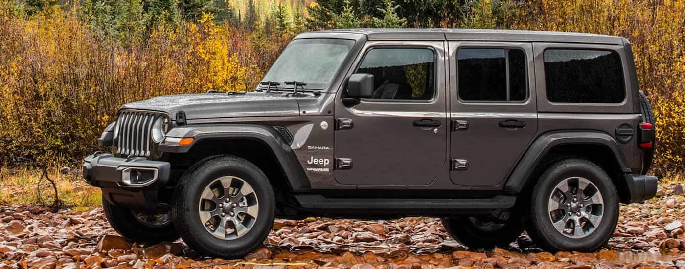 A grey 2021 Jeep Wrangler Sahara Unlimited is shown from the side parked on a brown rocky trail.