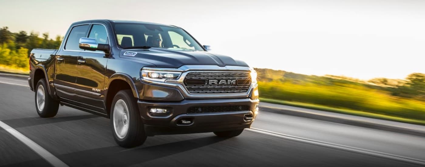 A grey 2020 Ram 1500 is shown driving on a road lined with grass after viewing a used Ram for sale near you.