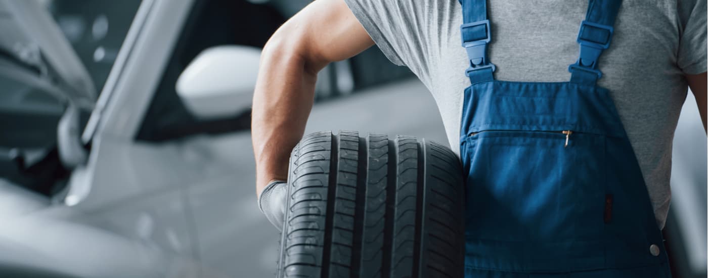 A mechanic is shown holding a tire at a repair shop.