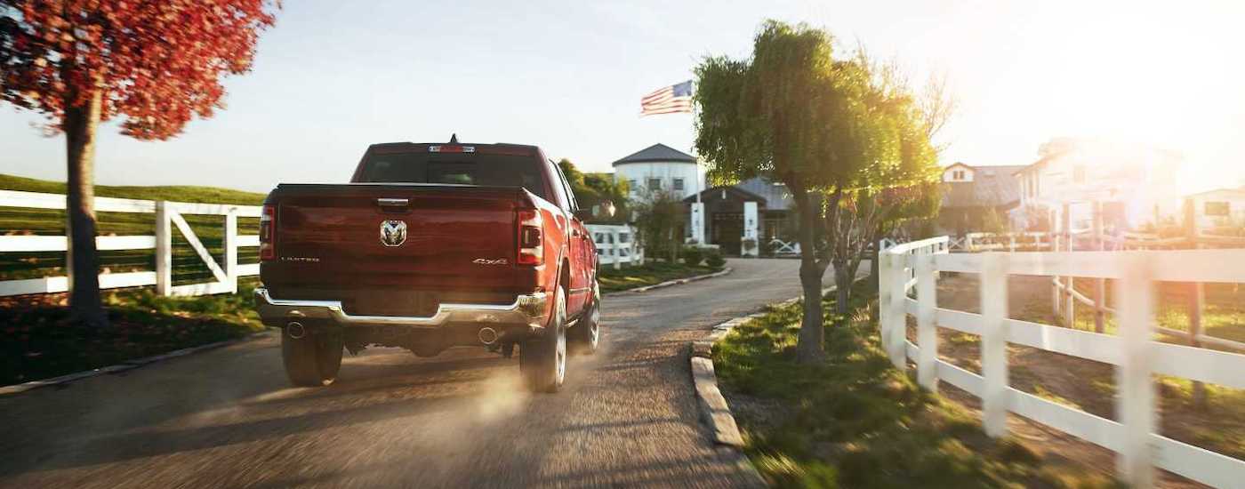 A red 2020 Ram 1500 Limited is shown driving toward a farm after leaving a Wilmington Ram dealer.